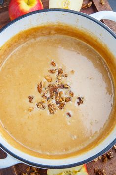 a bowl of soup with apples and nuts on the side