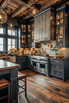 a large kitchen with wooden floors and black cabinets is pictured in this image, there are two stools at the center of the room