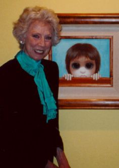 a woman standing next to a painting of a doll