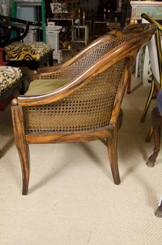 a wooden chair sitting on top of a floor next to a pile of chairs in a room