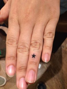 a woman's hand with a tiny black star tattoo on it