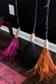 three tasseled brooms sitting next to each other on the floor