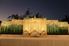 an outdoor stage set up for a wedding with white and green decorations on the wall