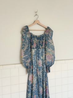 1970s blue prairie dress with a beautiful pink floral print . features a smocked bust and wrist, balloon sleeves and a sash that ties in the back. fully lined. zipper closure up back. in amazing vintage condition with no rips tears or stains.  measurements are taken with garment lying flat (inches)  Please note bust is smocked so measurements are flexible bust 27'  waist 26' sleeve 26' length 56.5' 70s Floral, Pink Floral Print, Prairie Dress, Balloon Sleeves, Dress Clothes For Women, Dresses Xs, Pink Floral, Smocking, Floral Print