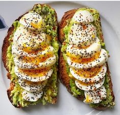 two pieces of bread with eggs and other toppings on it sitting on a plate