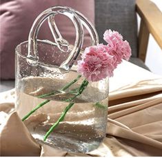 pink carnations are in a clear glass vase with water and ice cubes