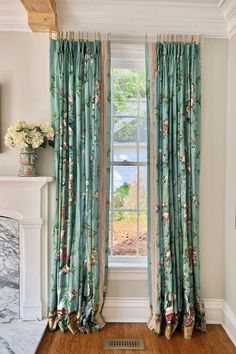 a living room with a fireplace and floral curtains