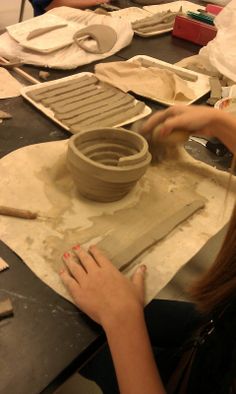 a woman is working with clay on a potter's wheel