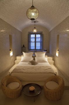 a bed sitting in the middle of a bedroom next to two chairs and a table