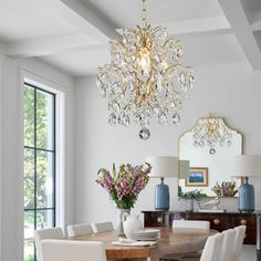 a dining room table with white chairs and a chandelier hanging from the ceiling