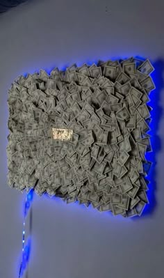 a large piece of art made out of dollar bills with blue light coming from it