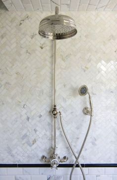 a shower head and handset in a bathroom with white tiles on the wall behind it