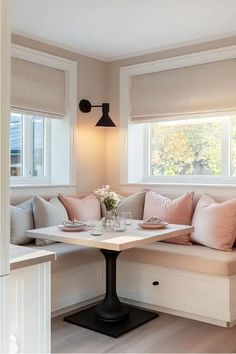 a living room filled with furniture next to a window covered in pink and white pillows