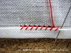 a close up of a piece of white fabric with red stitching on the side