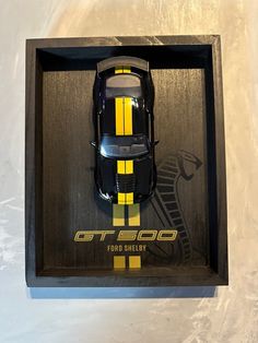 a toy car in a black box with yellow stripes on the front and back sides