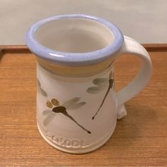 a white and blue coffee mug sitting on top of a wooden table