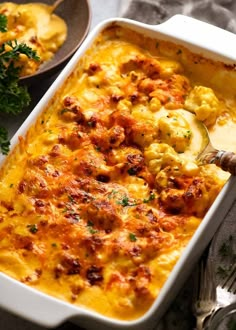 a casserole dish filled with macaroni and cheese, garnished with parsley