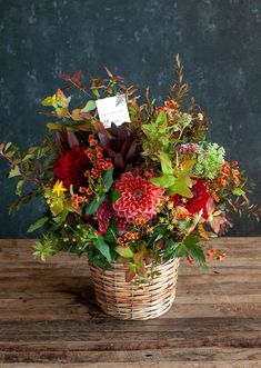 a basket filled with lots of flowers on top of a wooden table