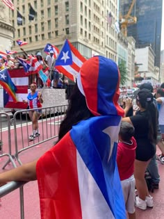 a woman in a red, white and blue cape is looking at the crowd from behind a barricade