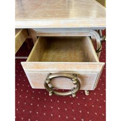 a white desk with two drawers and a metal handle on the bottom drawer, sitting on a red carpeted floor