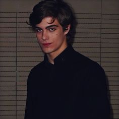 a young man in a black shirt looking at the camera