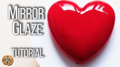 a red heart sitting on top of a white plate with the words mirror glaze