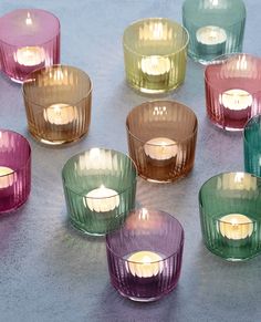 many different colored glass candles on a table