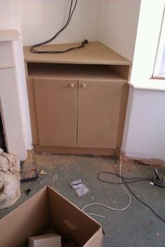 an empty room with boxes and wires on the floor in front of a cabinet that's missing