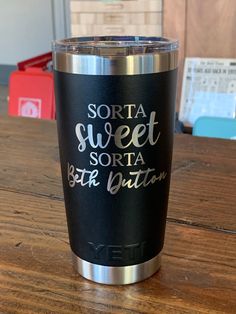 a black and silver yeti cup sitting on top of a wooden table with writing