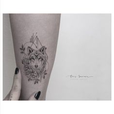 a woman's leg with a wolf and roses tattoo on the side of her thigh