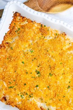 a cheesy casserole dish on a white plate with a wooden spoon