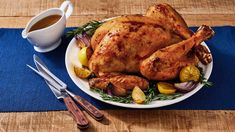 a roasted chicken on a plate next to a cup of coffee and utensils