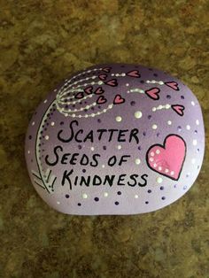 a painted rock that says, scatter seeds of kindness with hearts and dots on it