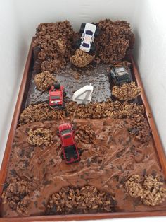 there are many toy cars in the middle of a cake that is made to look like dirt