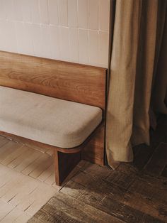 a wooden bench sitting on top of a hard wood floor next to a shower curtain