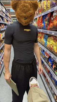 a man wearing a teddy bear mask in a grocery store aisle with his back to the camera