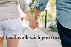 two people holding hands while walking down the street