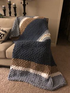 a blue and white blanket sitting on top of a couch next to a pillow in a living room