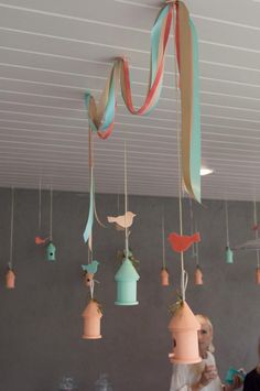 some birds are hanging from the ceiling with ribbons