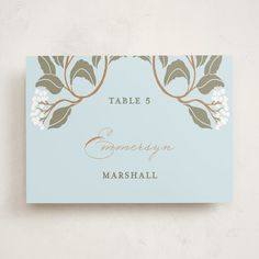 a place card with leaves and flowers on the front, in pale blue color scheme