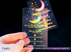 a person holding up a plastic business card with the moon and stars on it in front of them