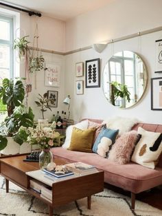 a living room filled with furniture and lots of plants on the windows sills