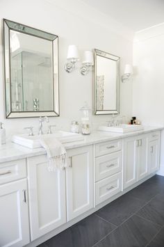 a bathroom with two sinks, mirrors and lights on the wall above them is shown