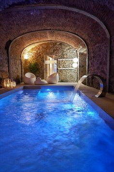 an indoor swimming pool with blue lights and water running from it's sides to the floor