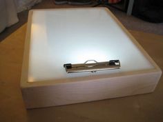 an electronic device sitting on top of a wooden table next to a white light box