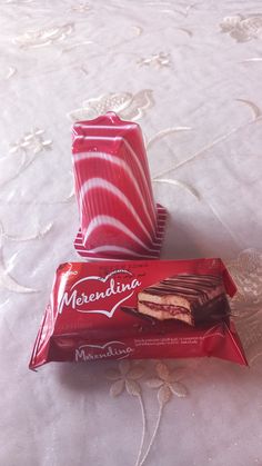 two pieces of chocolate cake sitting on top of a bed next to an empty wrapper