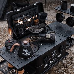 an open black box with many different items in it on top of a gravel ground