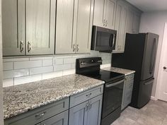 an empty kitchen with granite counter tops and black appliances in the center, along with white cabinets