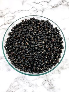 a glass bowl filled with blackberries on top of a marble counter