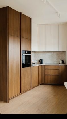 an empty kitchen with wooden cabinets and white counter tops, along with wood flooring